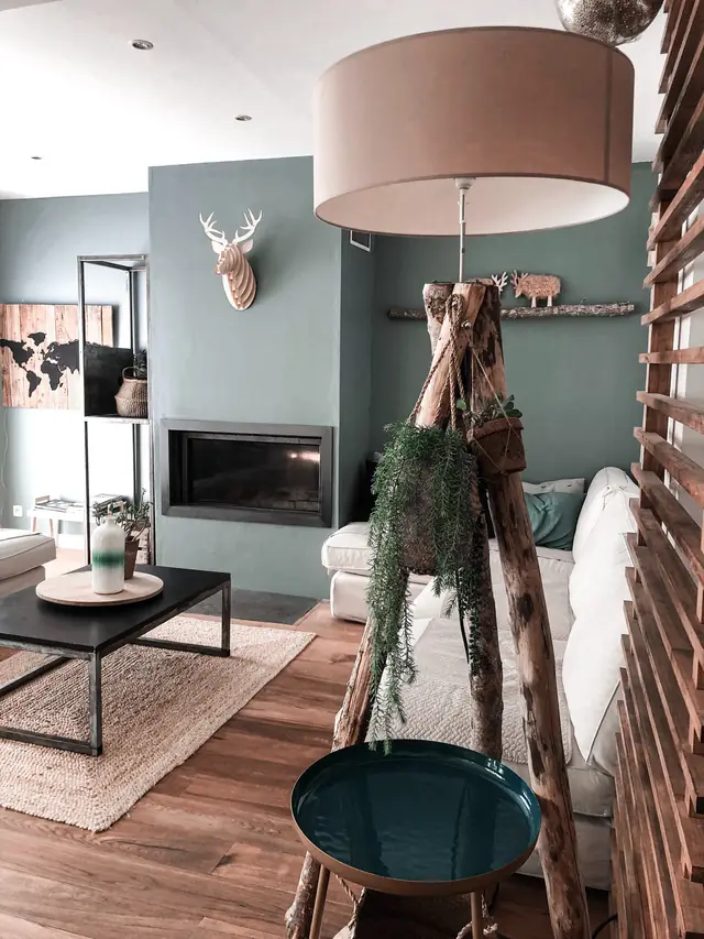 Sage-grey living room around a linear fireplace, a mounted deer head and a jute rug