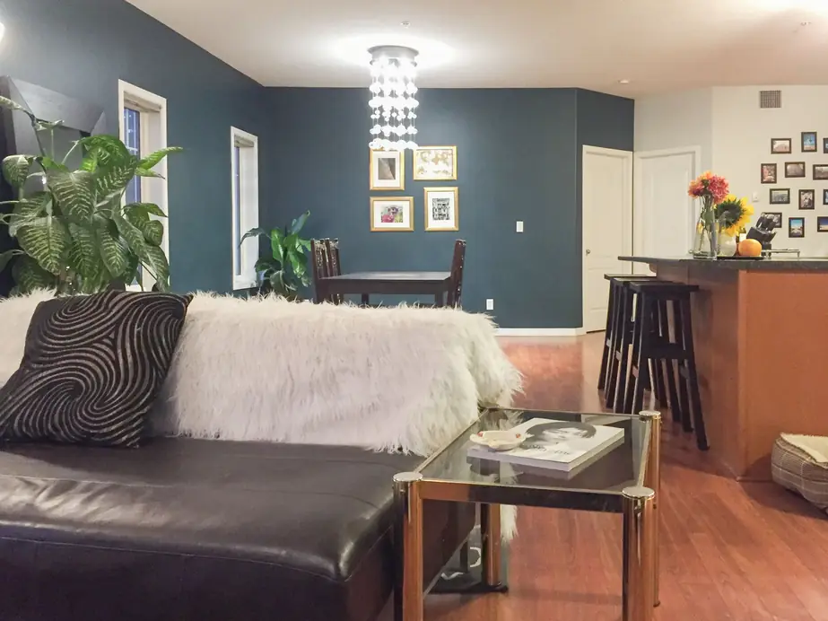 Teal-navy living and dining room with a white fur throw over a dark sofa